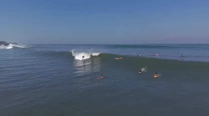 Surfistas esperando en el lineup mientras rompe una ola en Santa Teresa