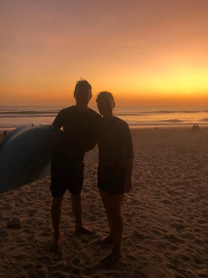 Dos surfistas en la playa al atardecer
